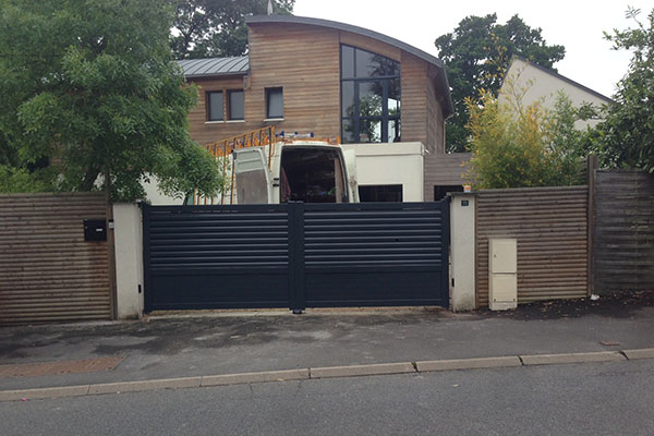 Photo d'un portail battant en aluminium devant une maison d'architecte